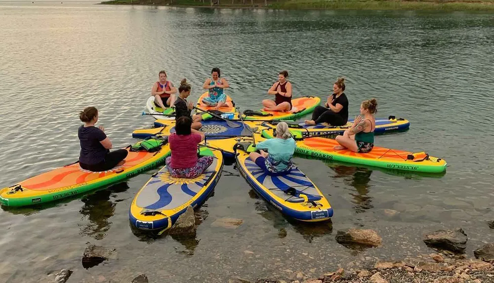 A group of people are practicing yoga on stand-up paddleboards on calm water