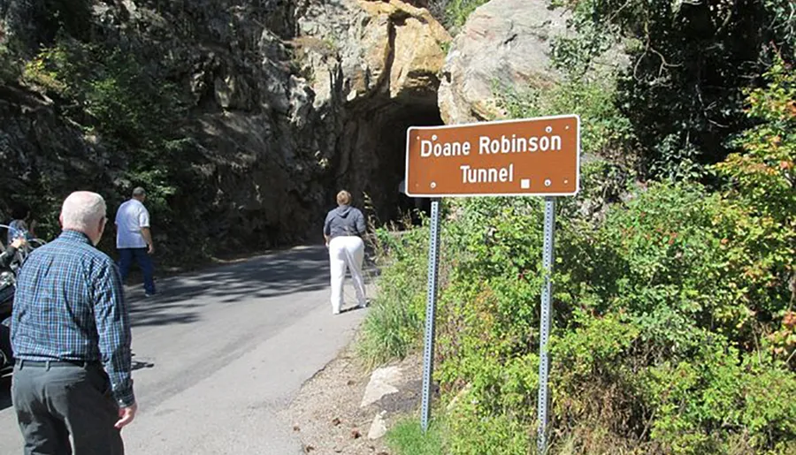 The image shows several people walking near the entrance to the Doane Robinson Tunnel, which is indicated by a nearby sign.