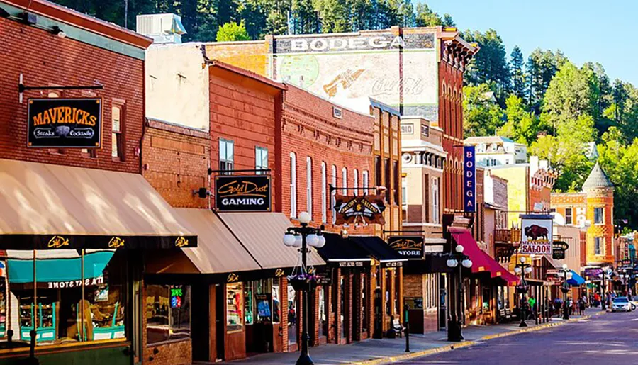This image shows a vibrant and colorful street lined with historic-looking buildings featuring various business signs, such as Mavericks Steaks Cocktails, Gold Dust Gaming, and Saloon, suggesting a downtown area with a mix of dining and entertainment options, possibly in a town with a historic or western theme.