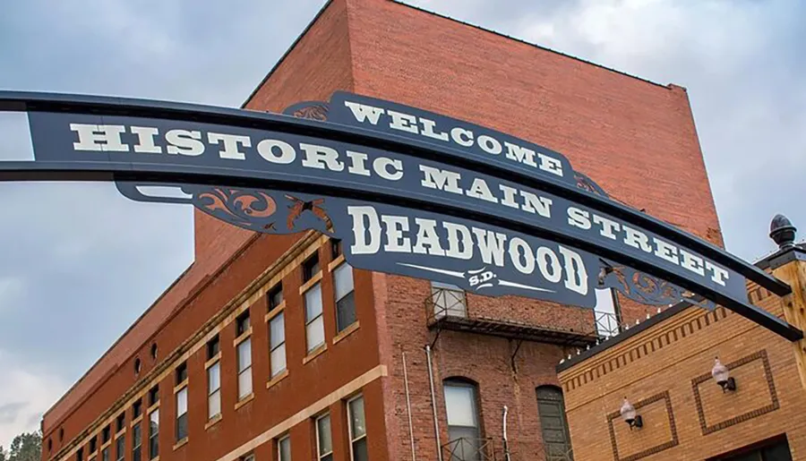 The image features an archway sign that reads Welcome to Historic Main Street Deadwood S.D. against the backdrop of a brick building.