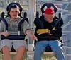 Two people are laughing and enjoying a ride on an amusement park attraction with metal sculptures of buffalo in the foreground