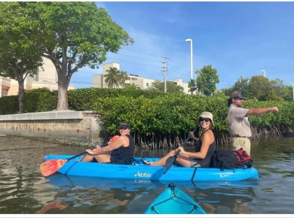 Three people are enjoying a sunny day out on the water while kayaking