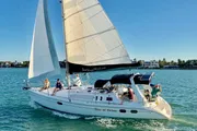 The image shows a group of people enjoying a sunny day on a sailboat named 