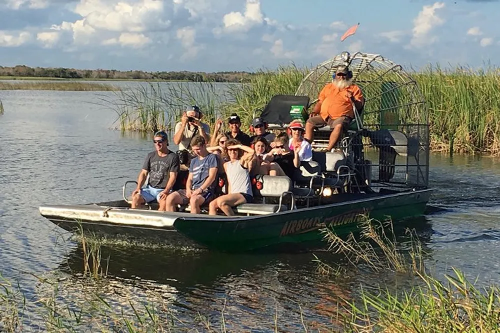 A group of people is enjoying an airboat tour through a marshy waterway