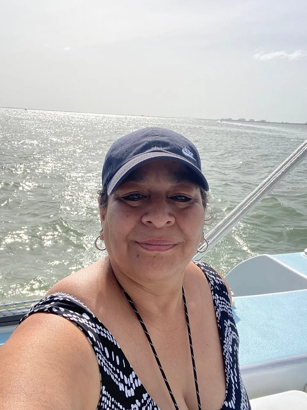 A person is taking a selfie on a sunny day while on a boat with shimmering water in the background