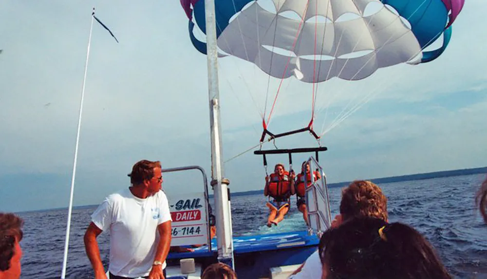 A parasailing participant is being launched from a boat into the sky as onlookers watch from the vessel