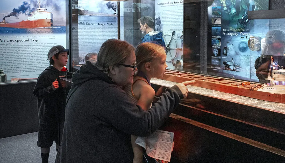 Visitors are engaged in examining a ship model and reading information on display at a maritime museum exhibit