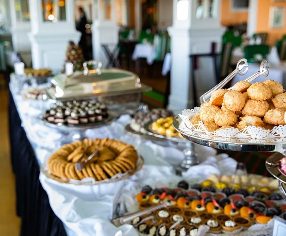 A buffet table is set up with a variety of desserts and sweets displayed elegantly in a well-lit room