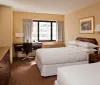 This image shows a tidy hotel room with a large bed a window with a city view a desk area and tasteful decorations creating a comfortable and inviting space