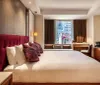 The image displays a modern and neatly arranged hotel room with a large bed plush pillows ambient lighting and a window with a city view