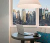 The image shows a modern and neatly arranged hotel room with a large bed stylized wall art and a view of the city outside the window