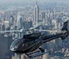 A helicopter is flying over a dense urban landscape with skyscrapers and a bridge in the background