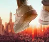 A pair of shoes against a city skyline with the impression of someone jumping or floating above the urban landscape at sunset