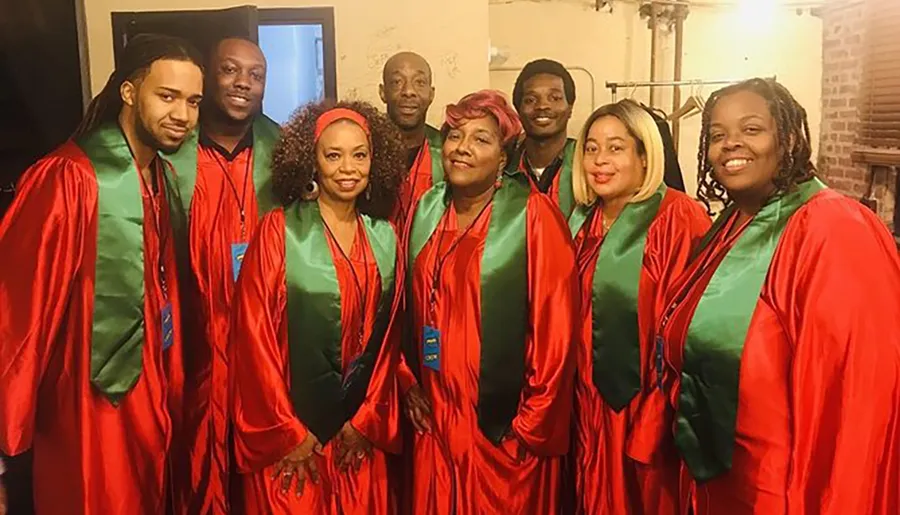 A group of people are smiling for the camera, wearing matching red and green choir robes.