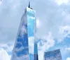 The image shows an artistic ring-shaped digital display with multiple screens labeled One World Trade Center set against a backdrop of large windows with a view of the sky and horizon