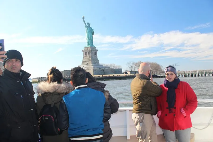 Tourists on a boat are viewing and taking photos of the Statue of Liberty.