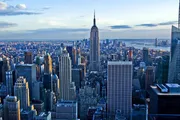 This image captures a panoramic view of New York City's skyline with the Empire State Building prominently featured in the center, during what appears to be late afternoon.