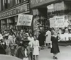 A group of people is marching in front of an F W Woolworth Co store carrying signs indicating a strike and a call for support from the public to not patronize the store