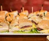 The image shows a platter of assorted cut sandwiches with toothpicks in them ready to be served at a gathering