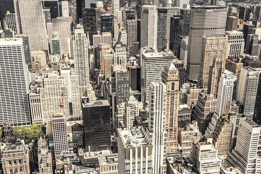 The image shows an aerial view of a dense cityscape with a multitude of skyscrapers and buildings, characteristic of a bustling metropolitan area.