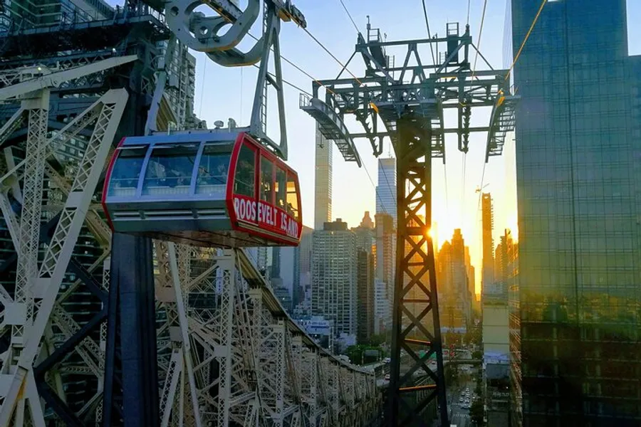 An aerial tramway cabin traverses above a cityscape against the backdrop of a sunset.
