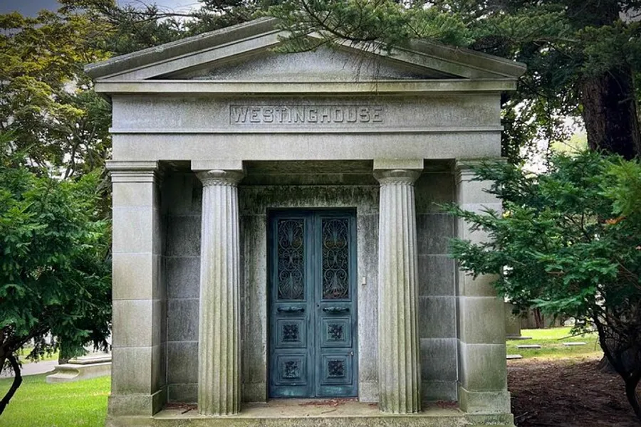 The image shows a stately mausoleum with the name WESTINGHOUSE engraved above the ornate metal doors, surrounded by greenery in what appears to be a peaceful cemetery setting.