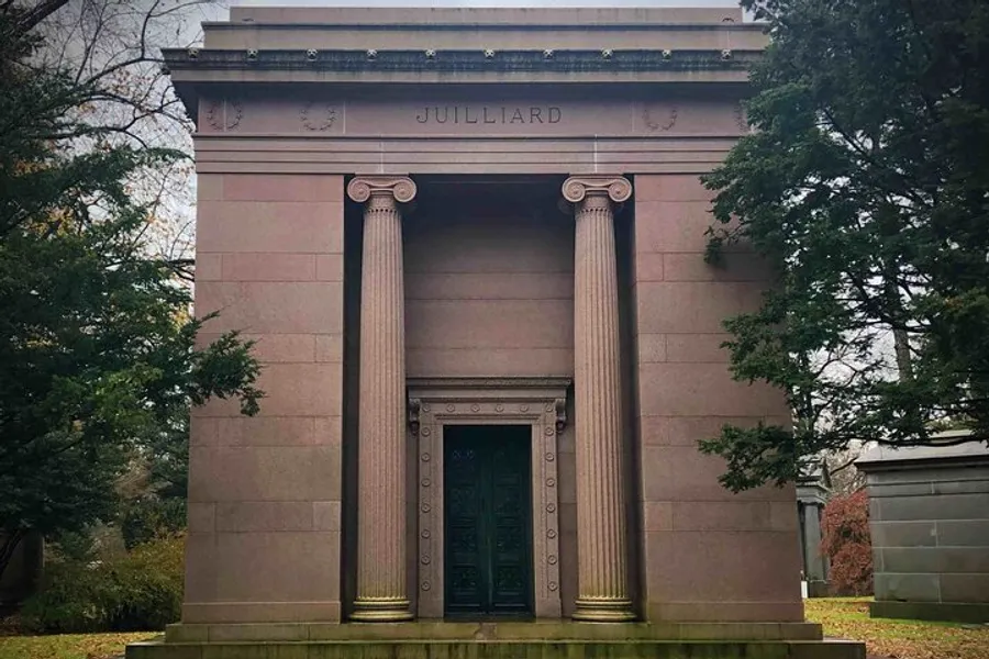 The photo depicts a stately mausoleum with the name Julliard engraved at the top, featuring classic architectural elements such as tall columns and an ornate bronze door.