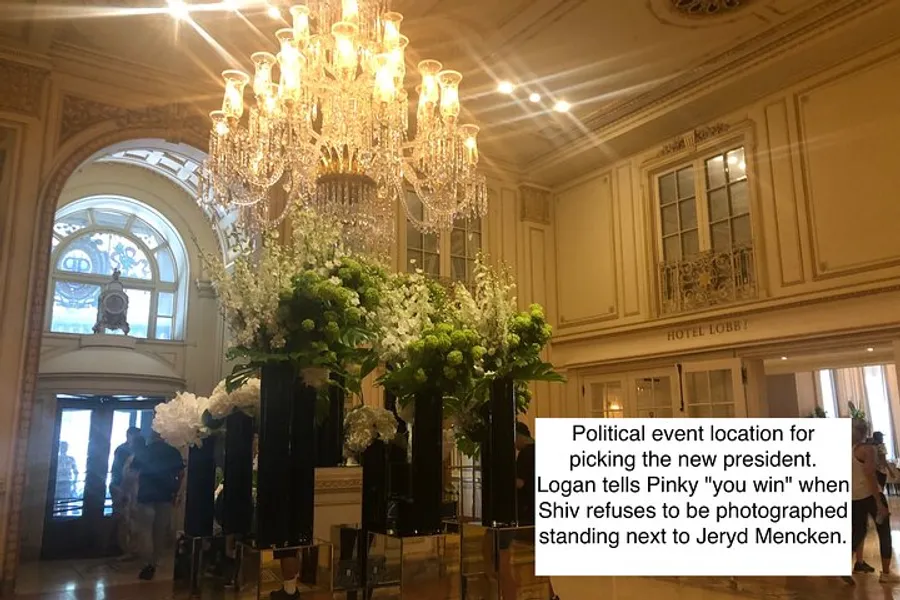 The image shows an elegant hotel lobby with chandeliers and floral decorations, and there is a caption overlay describing a scene from a political event.