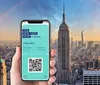 A hand holds up a smartphone displaying a New York Pass ticket with a QR code in front of a panoramic view of New York City
