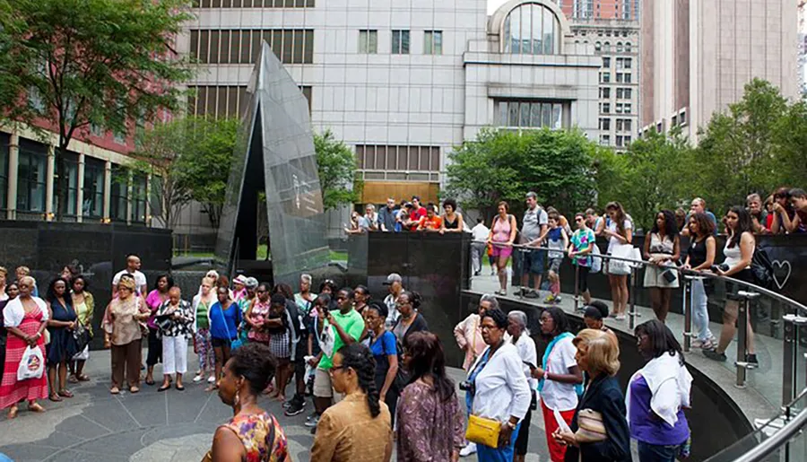 People are gathered around an urban outdoor memorial, possibly waiting in line or reflecting.