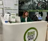 A person is seated behind the counter of a bike rental shop with information on bike rentals and tours visible in the background