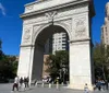 The image shows the Washington Square Arch in New York City on a sunny day with people walking around the open plaza