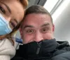 A man and a woman both wearing masks are playfully posing for a close-up selfie with smiling eyes suggesting a moment of lightheartedness or humor