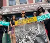 A group of people are smiling and holding street signs with names of African American leaders and activists in front of the Harlem Heritage Tourism and Cultural Center