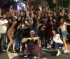 A diverse group of cheerful people pose for a lively group photo on a city street at night