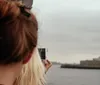 A person is photographing the Statue of Liberty with a smartphone