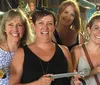 Four women are smiling for the camera while holding large sculpting chisels in a workshop setting