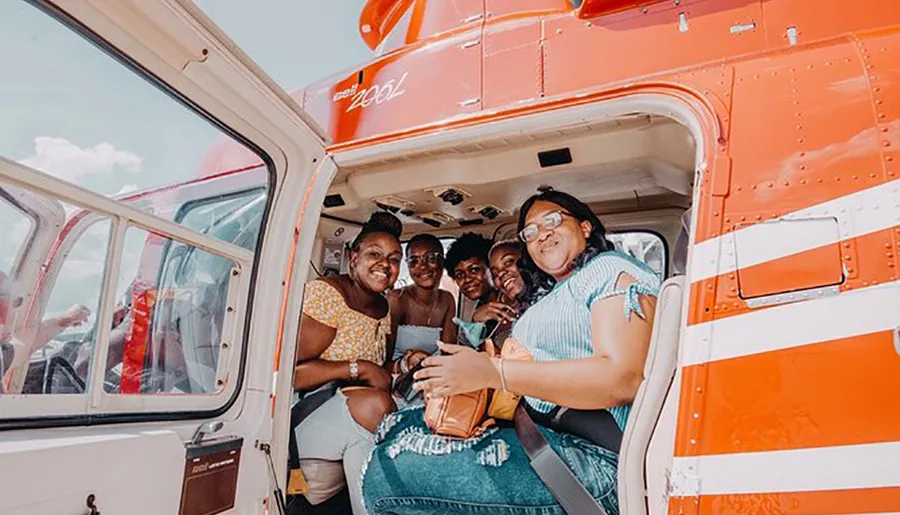 A group of happy people are posing for a photo inside a helicopter with the doors open.
