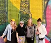 Four people are smiling in front of a colorful graffiti wall