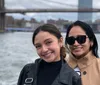 Two smiling individuals pose for a photo with a prominent bridge in the background likely taken on a boat or waterfront