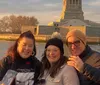 A group of people are capturing the view of the Statue of Liberty with their phones at sunset