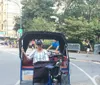 Three people are enjoying a ride through an urban street in pedal-powered rickshaws