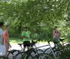 A group of people is standing near parked bicycles possibly engaged in a discussion or getting instructions from the individual gesturing with his hand