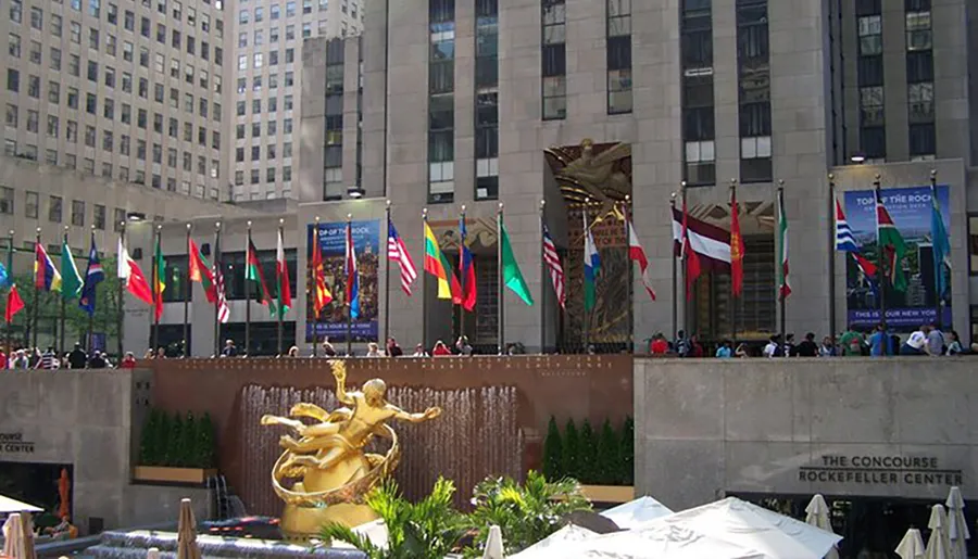 This image shows the iconic golden Prometheus statue overlooking the skating rink at Rockefeller Center, surrounded by national flags.