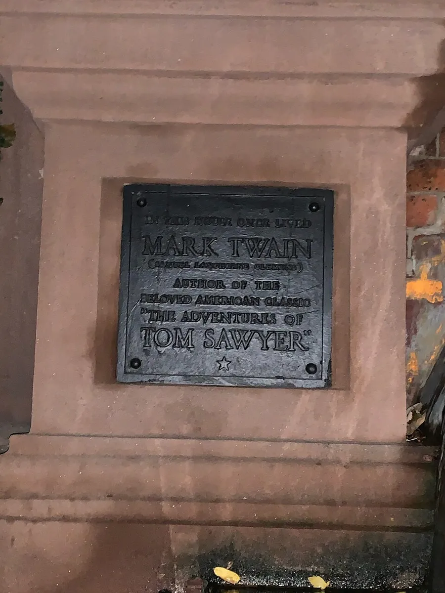 The image shows a commemorative plaque honoring Mark Twain, the author of the beloved American classics The Adventures of Tom Sawyer and others, affixed to a stone wall or structure.