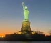 The Statue of Liberty is illuminated against a twilight sky showcasing a gradient from blue to warm orange