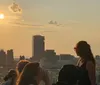 This image captures a group of people enjoying a scenic sunset over a city skyline