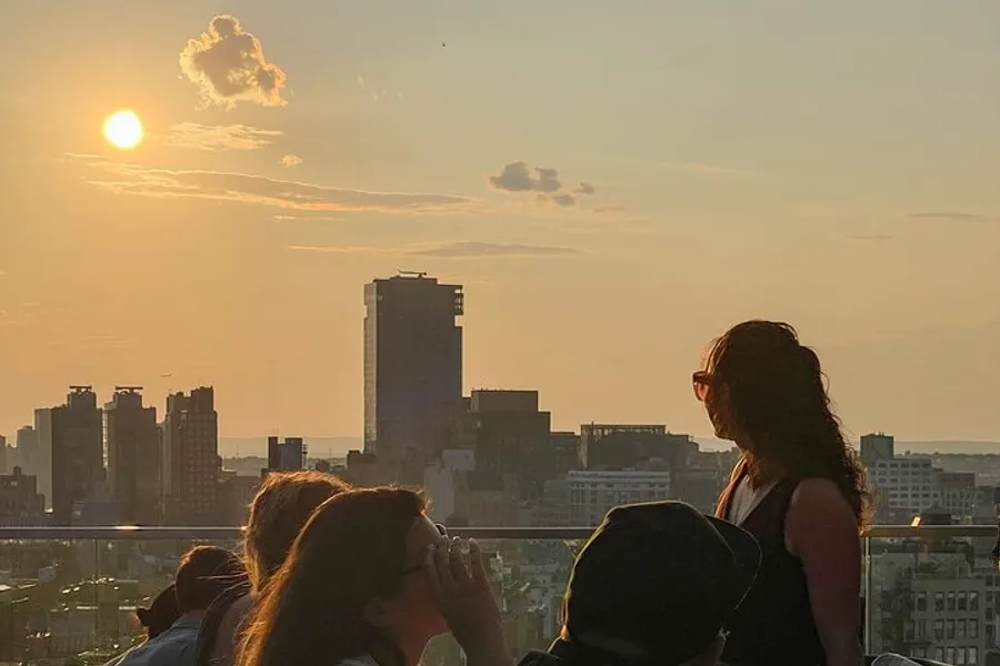 This image captures a group of people enjoying a scenic sunset over a city skyline.