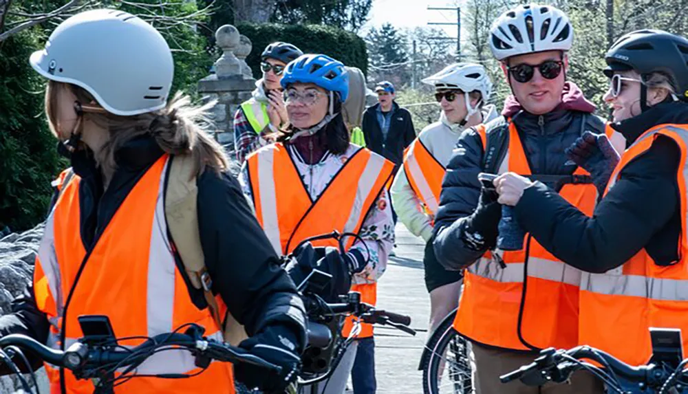A group of individuals wearing helmets and high-visibility vests seem to be engaged in an outdoor biking event or safety training session
