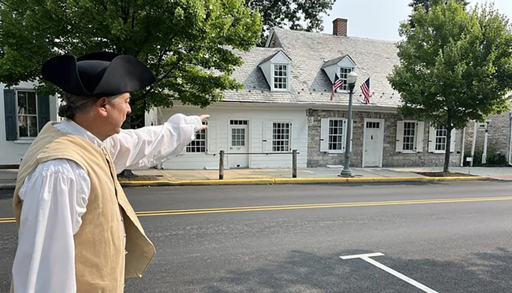 A person dressed in colonial-era clothing is pointing across a street toward a stone building adorned with American flags